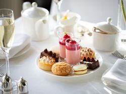 Elegant plate of assorted desserts and a glass of champagne on a white tablecloth.