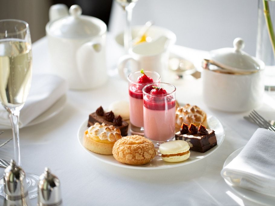 Elegant plate of assorted desserts and a glass of champagne on a white tablecloth.