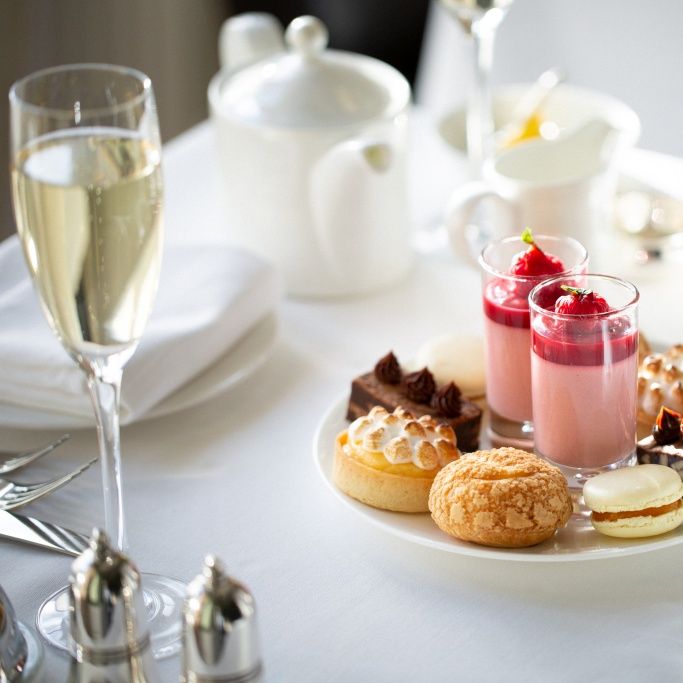 Elegant plate of assorted desserts and a glass of champagne on a white tablecloth.