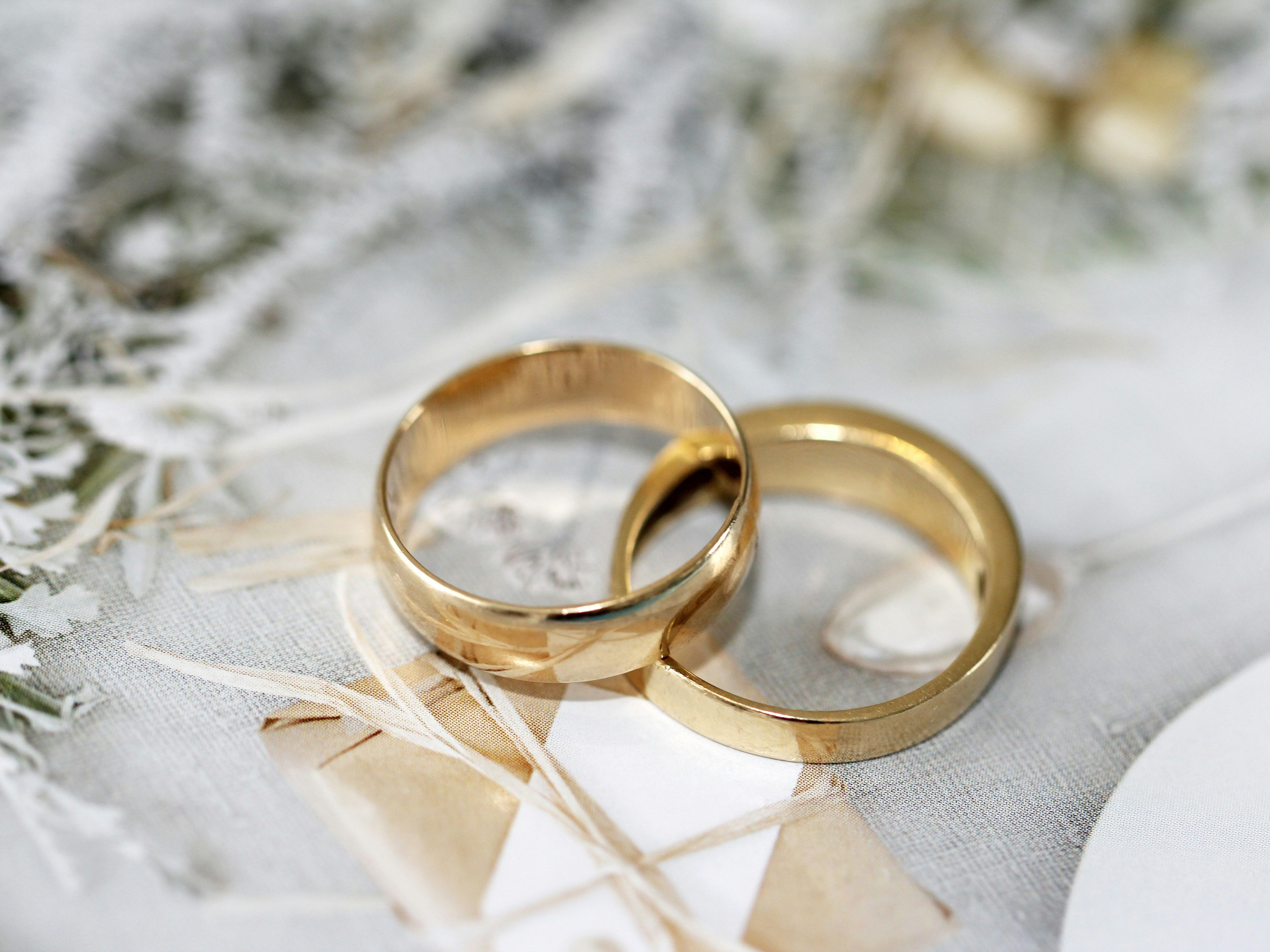 Two gold wedding rings placed on a decorative surface