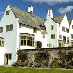 Large white historic house with steep roofs and multiple chimneys, set against a blue sky
