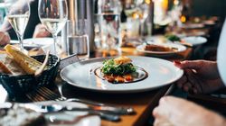 Gourmet dish served on a white plate at a fine dining restaurant with wine glasses and bread on the table.