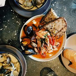 Overhead view of seafood dishes including mussels, shrimp, clams, toasted bread, and creamy pasta