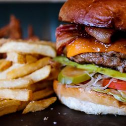 Close-up of a cheeseburger with bacon and a side of French fries