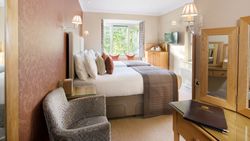 Elegant twin hotel room with two beds, a window seat, and wooden furniture.