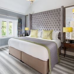 Modern hotel room with a large bed, striped carpet, desk, window, and stylish décor