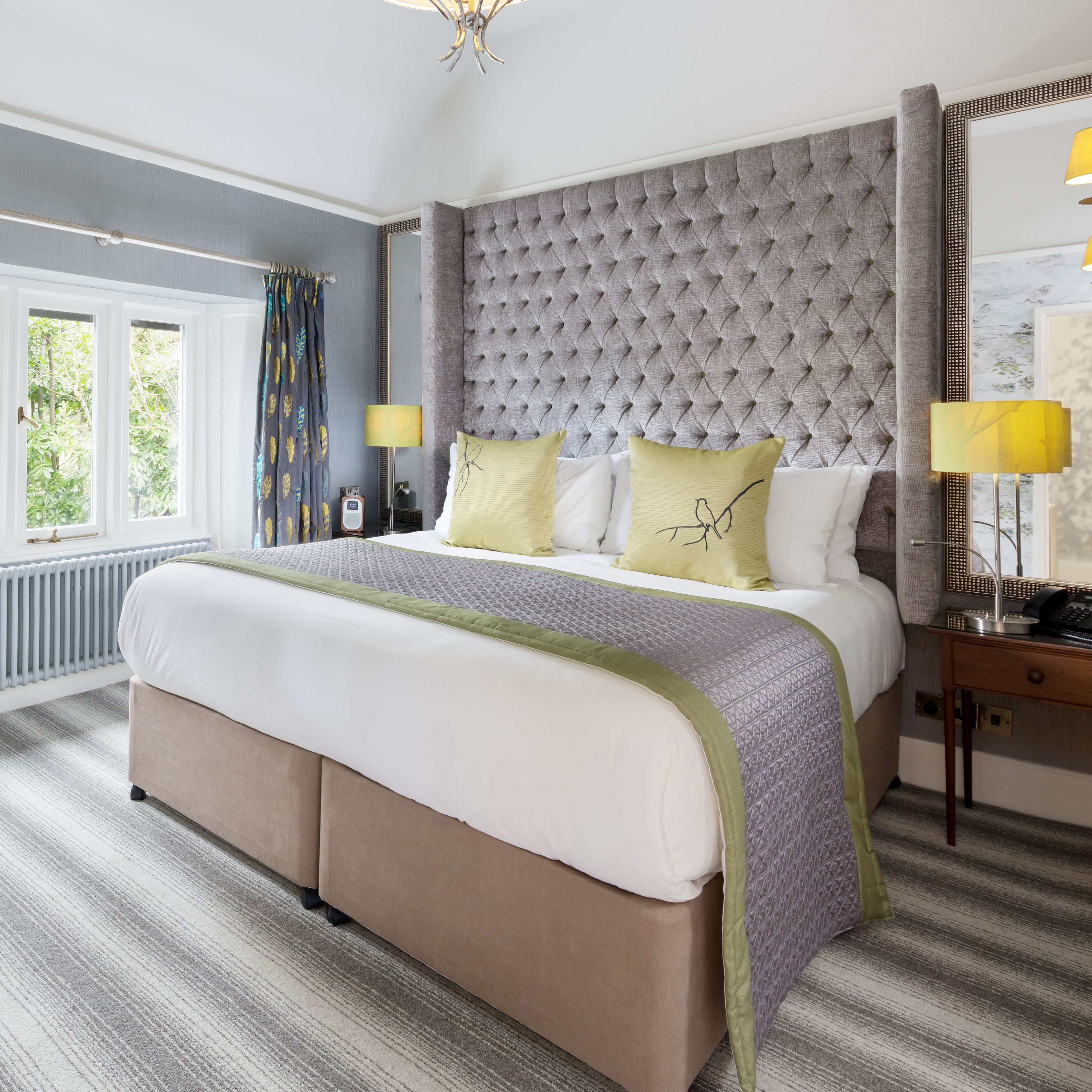 Modern hotel room with a large bed, striped carpet, desk, window, and stylish décor