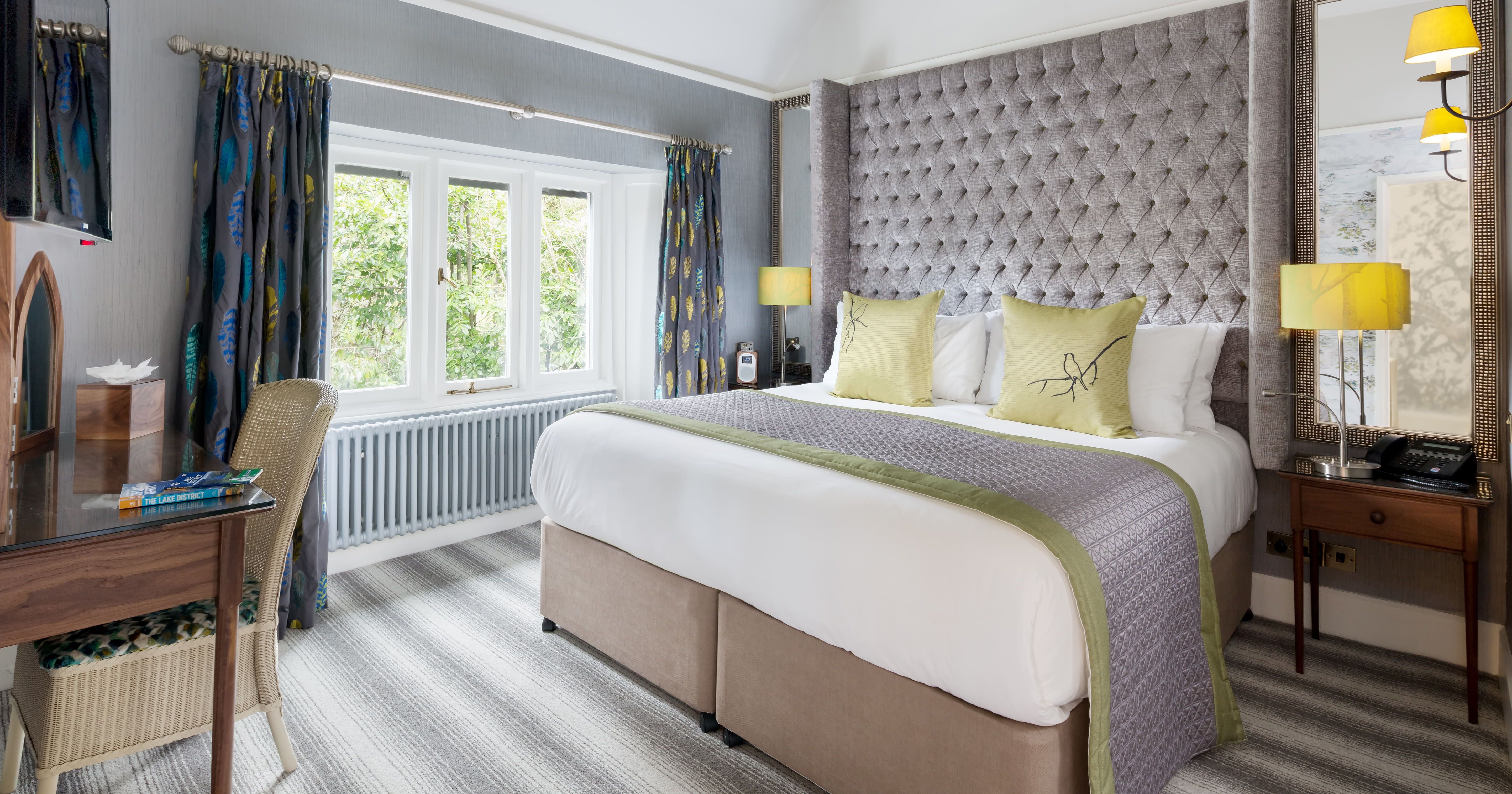 Modern hotel room with a large bed, striped carpet, desk, window, and stylish décor