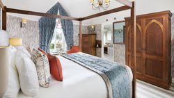 Luxury bedroom with a four-poster bed, blue and orange accents, and wooden furniture.