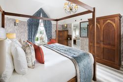Luxury bedroom with a four-poster bed, blue and orange accents, and wooden furniture.