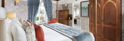 Luxury bedroom with a four-poster bed, blue and orange accents, and wooden furniture.
