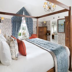 Luxury bedroom with a four-poster bed, blue and orange accents, and wooden furniture.