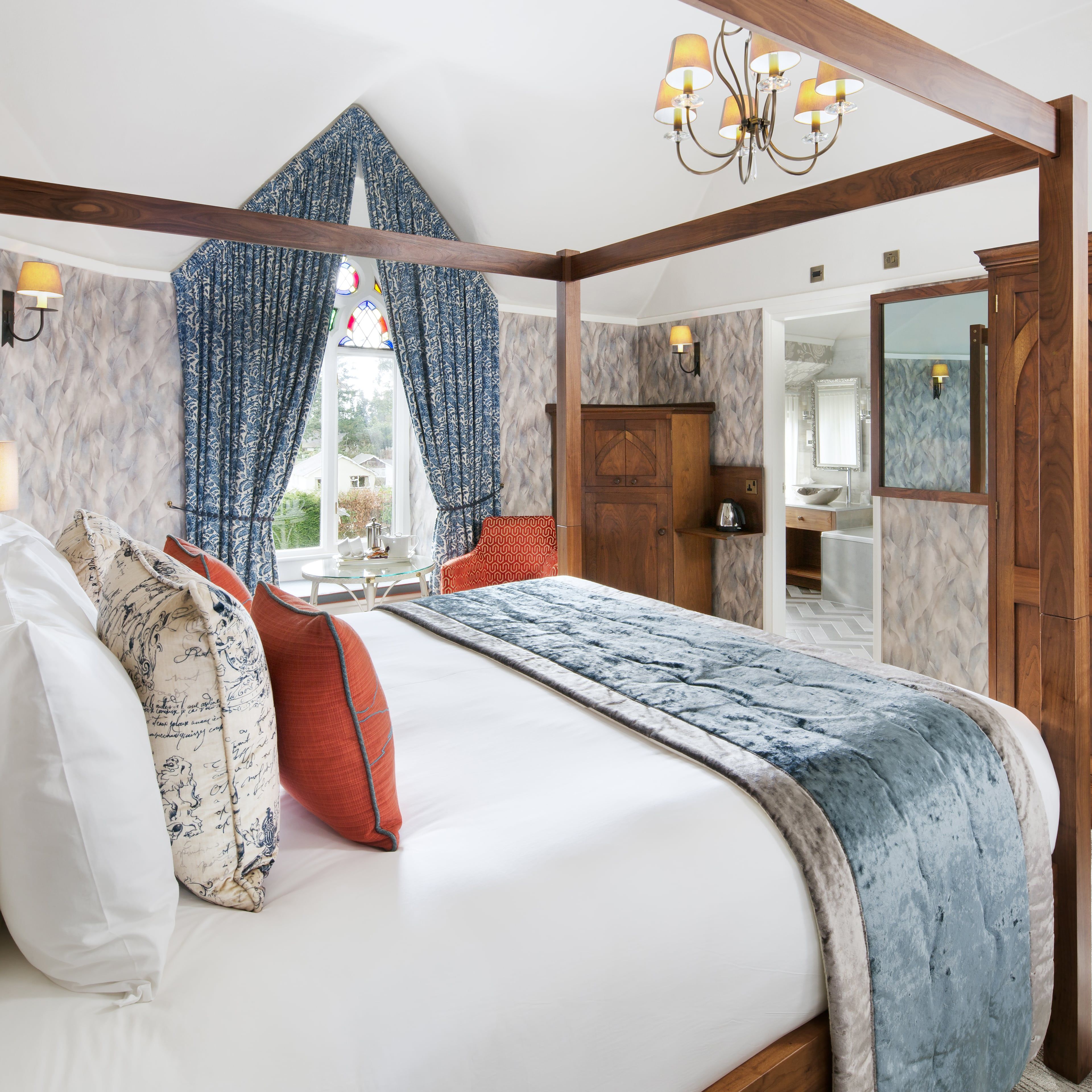 Luxury bedroom with a four-poster bed, blue and orange accents, and wooden furniture.