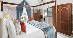 Luxury bedroom with a four-poster bed, blue and orange accents, and wooden furniture.
