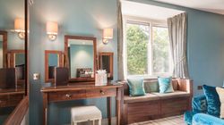 Elegant room with wooden vanity, window seat, and blue accents