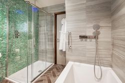 Modern ensuite bathroom with green mosaic tile shower and bathtub