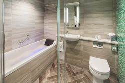 Modern ensuite bathroom with bathtub, sink, toilet, and glass shower