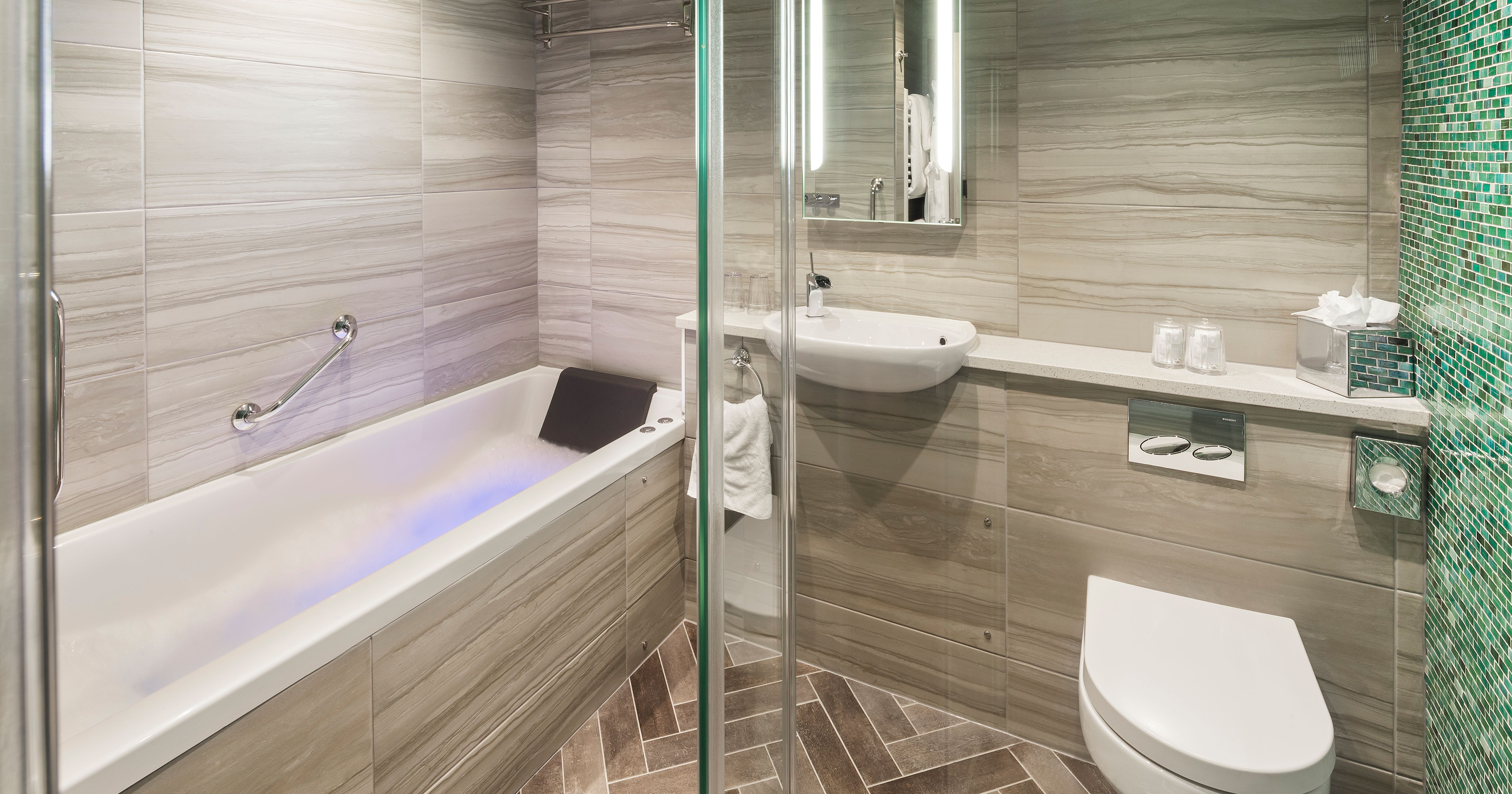 Modern ensuite bathroom with bathtub, sink, toilet, and glass shower