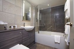 Modern bathroom with a bathtub, shower, sink, mirror, and towels