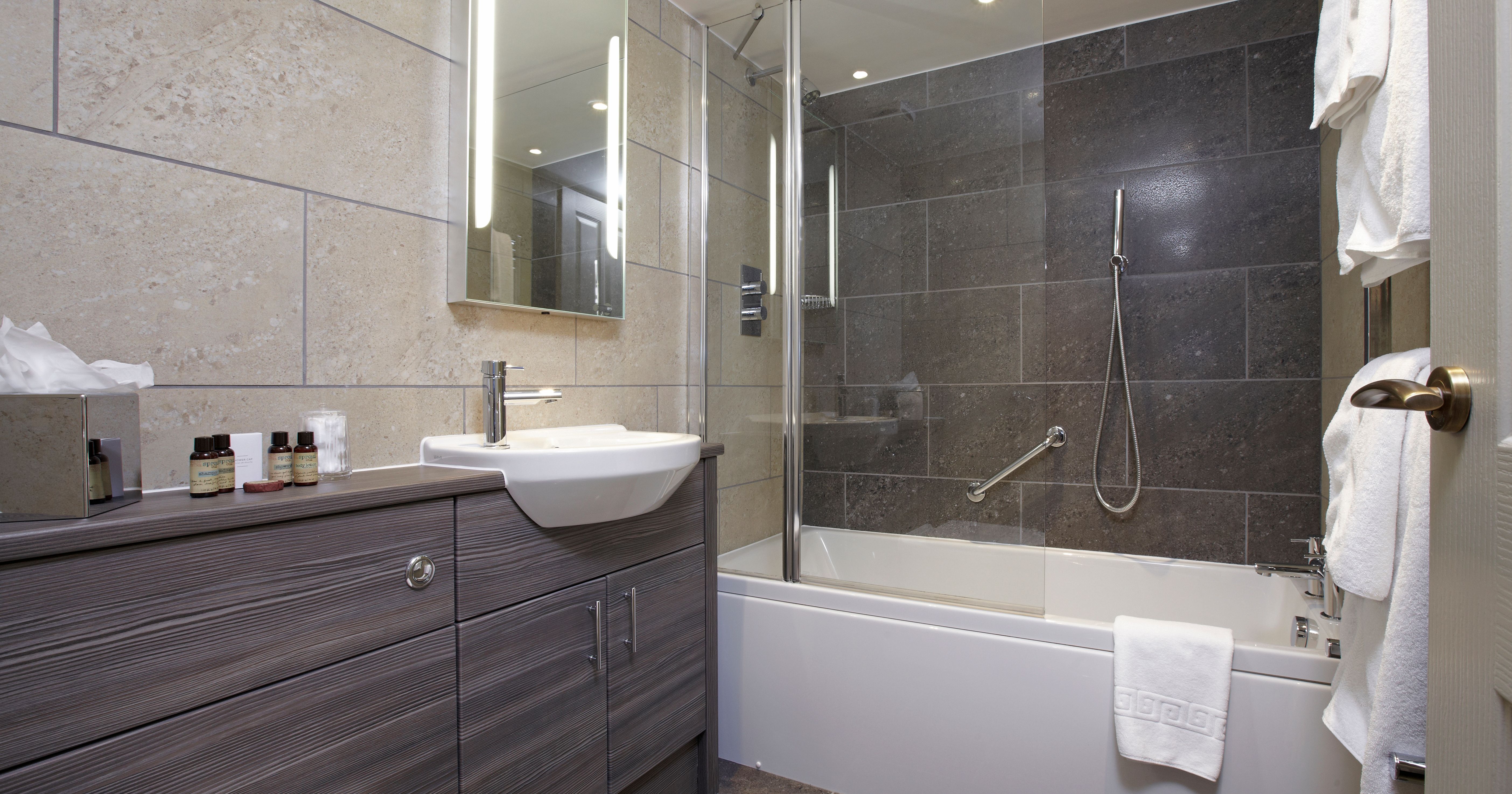 Modern bathroom with a bathtub, shower, sink, mirror, and towels