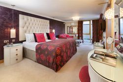 Elegant hotel bedroom with patterned bedspread, purple feature wall, and modern furnishings