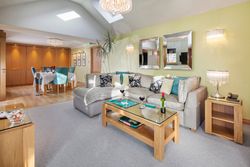 Modern lounge and dining room with a sectional sofa, glass coffee table, and dining area with teal chairs