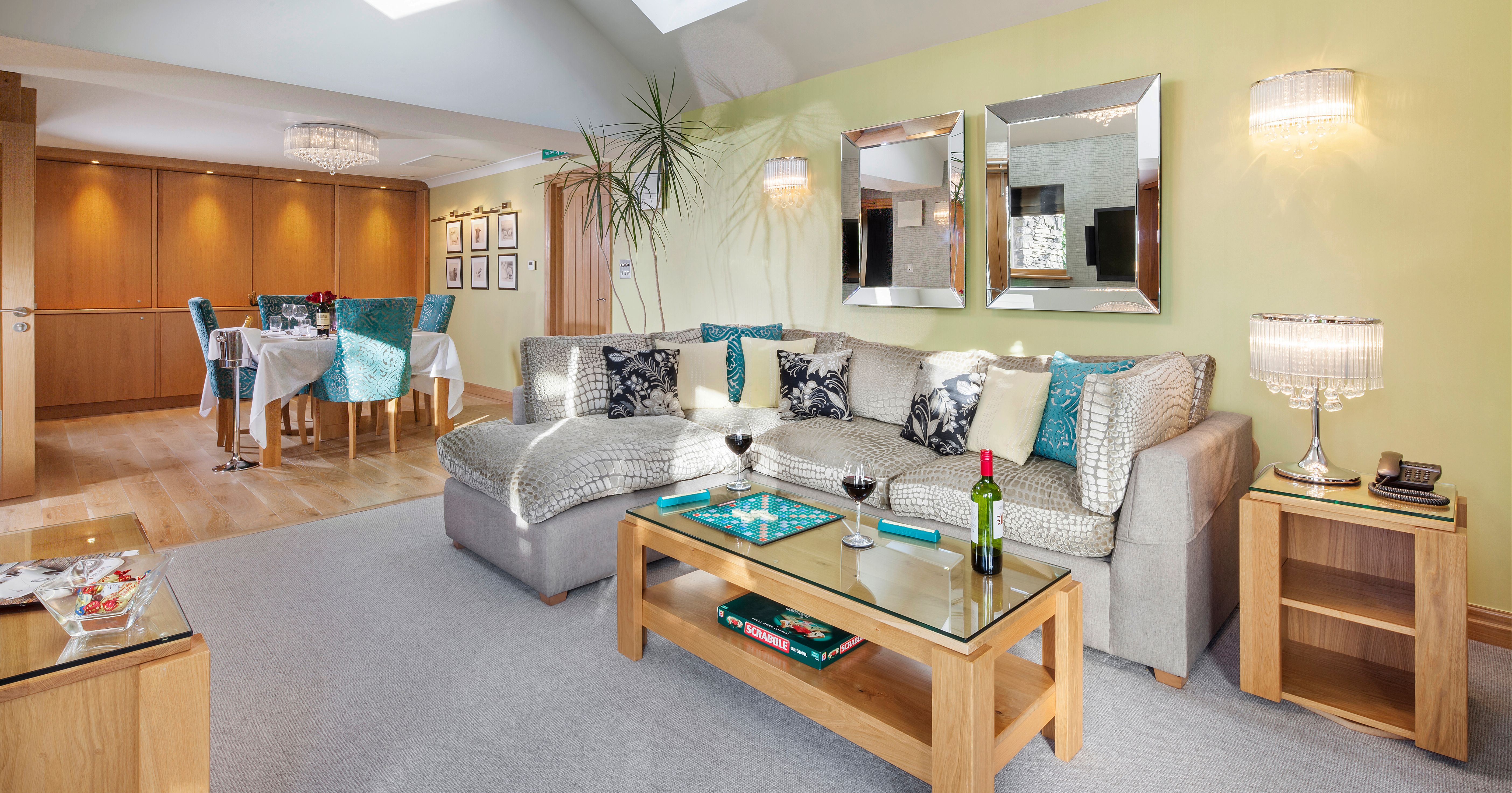 Modern lounge and dining room with a sectional sofa, glass coffee table, and dining area with teal chairs