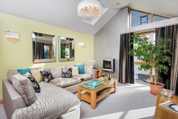 Modern lounge with sectional sofa, coffee table, fireplace, and large potted plant near window.