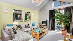 Modern lounge with sectional sofa, coffee table, fireplace, and large potted plant near window.