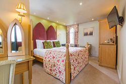 Bright and cozy hotel bedroom with floral bedding and unique red headboard