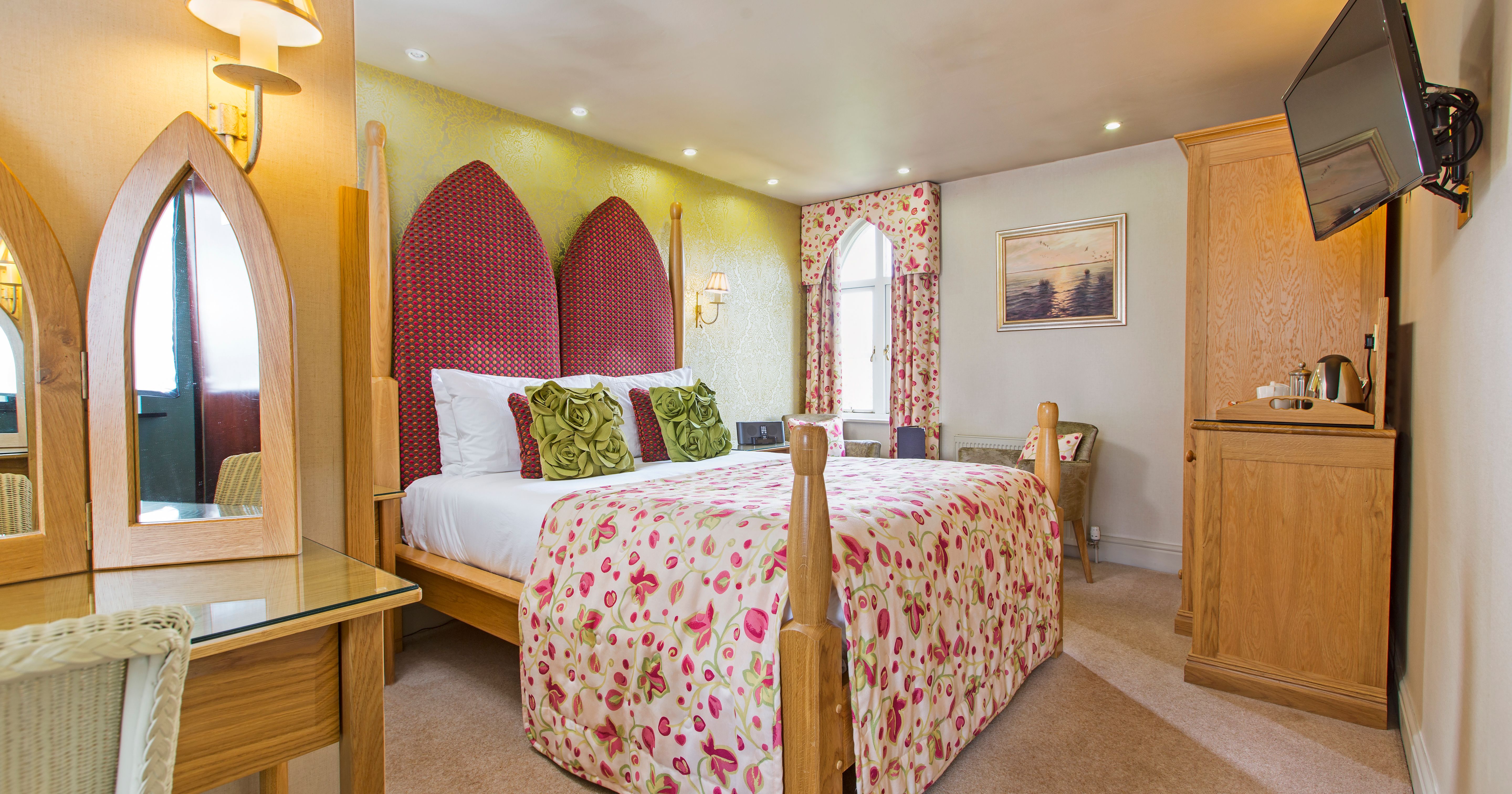 Bright and cozy hotel bedroom with floral bedding and unique red headboard