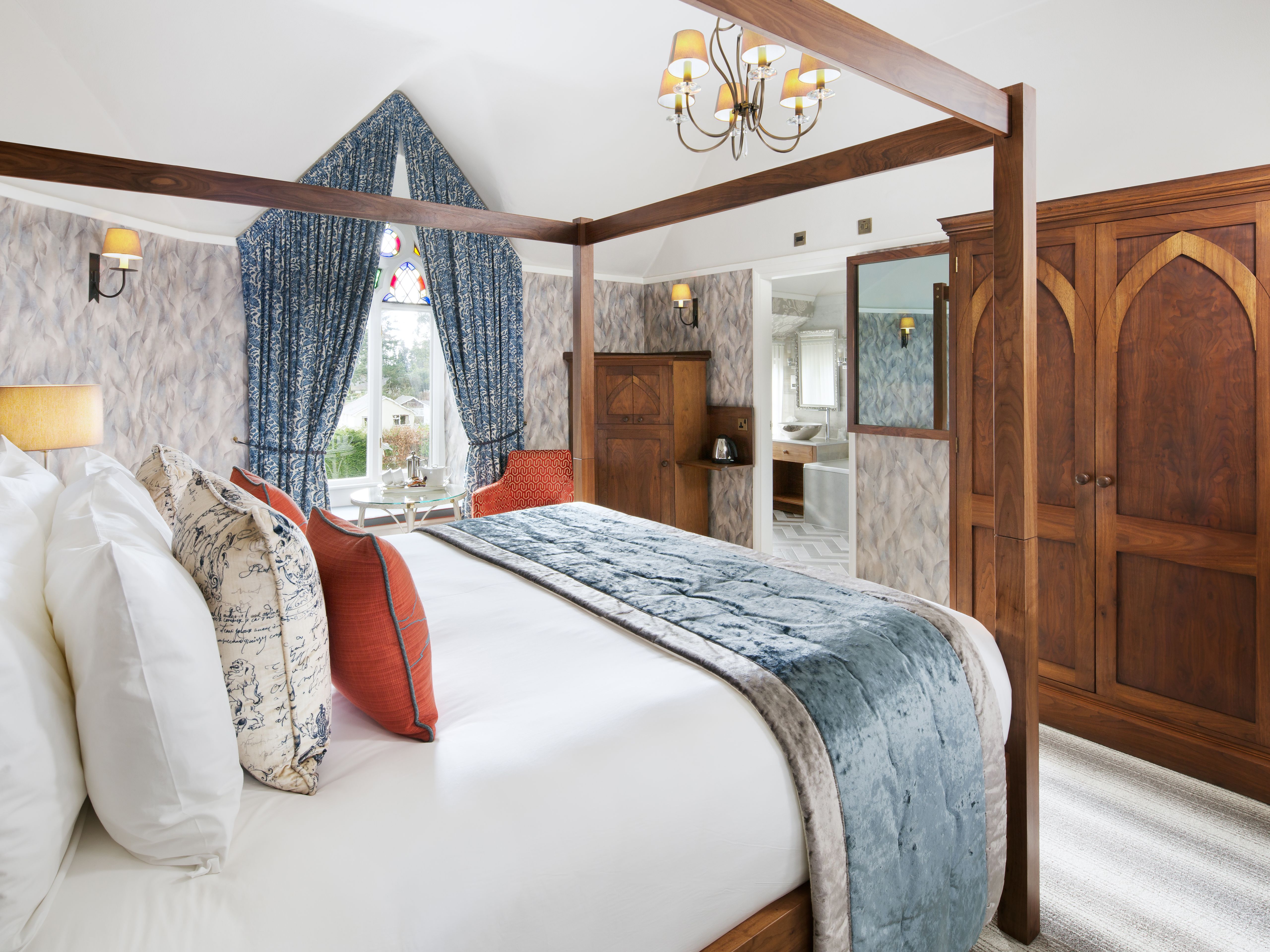 Elegant hotel bedroom with four-poster bed, plush pillows, and classic wooden furniture