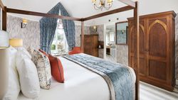 Elegant hotel bedroom with four-poster bed, plush pillows, and classic wooden furniture