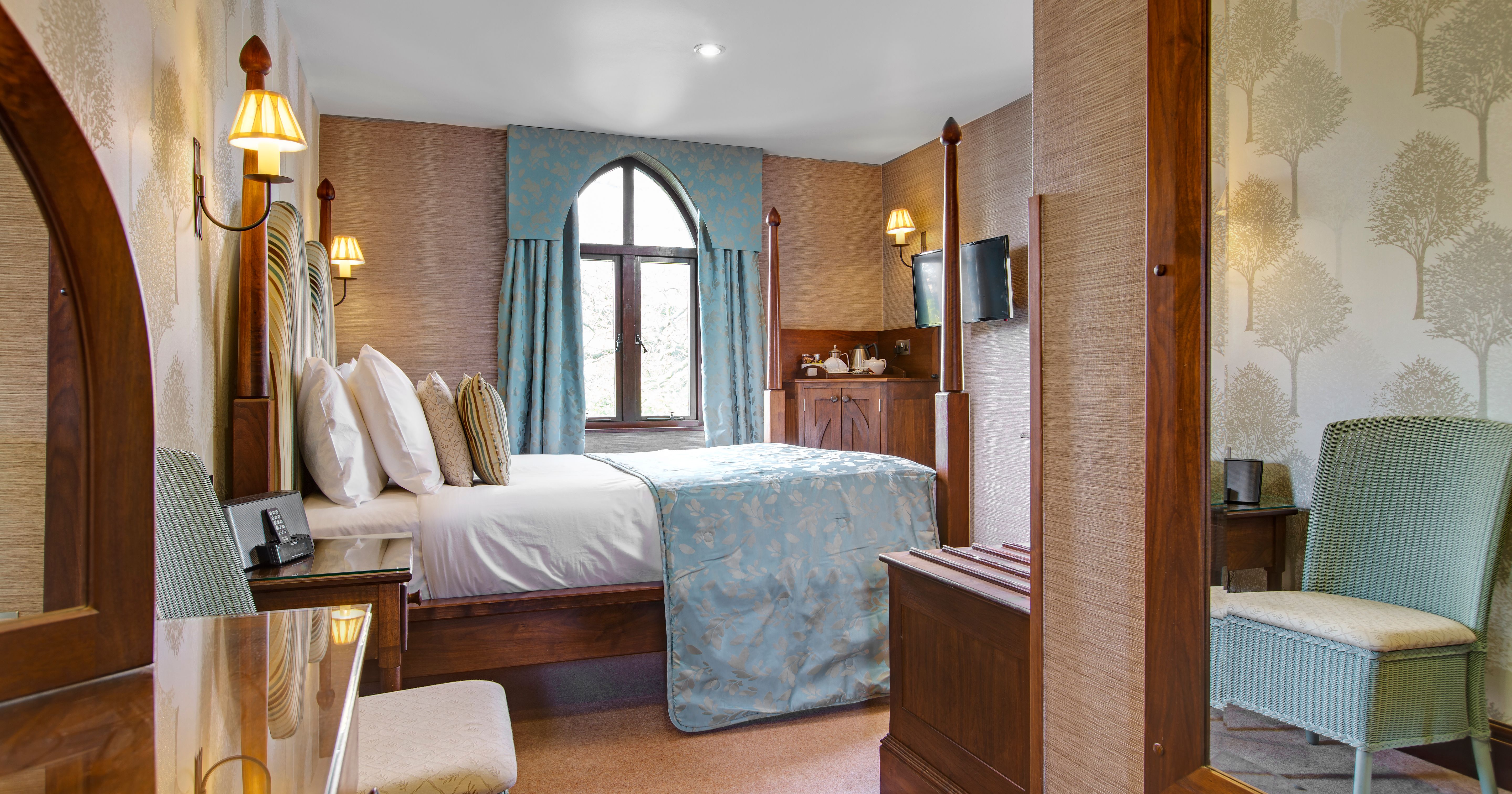 Cozy hotel bedroom with four-poster bed, blue accents and a window