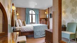 Cozy hotel bedroom with four-poster bed, blue accents and a window