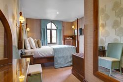 Cozy hotel bedroom with four-poster bed, blue accents and a window