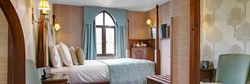 Cozy hotel bedroom with four-poster bed, blue accents and a window