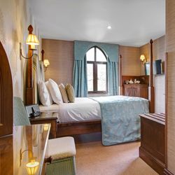 Cozy hotel bedroom with four-poster bed, blue accents and a window