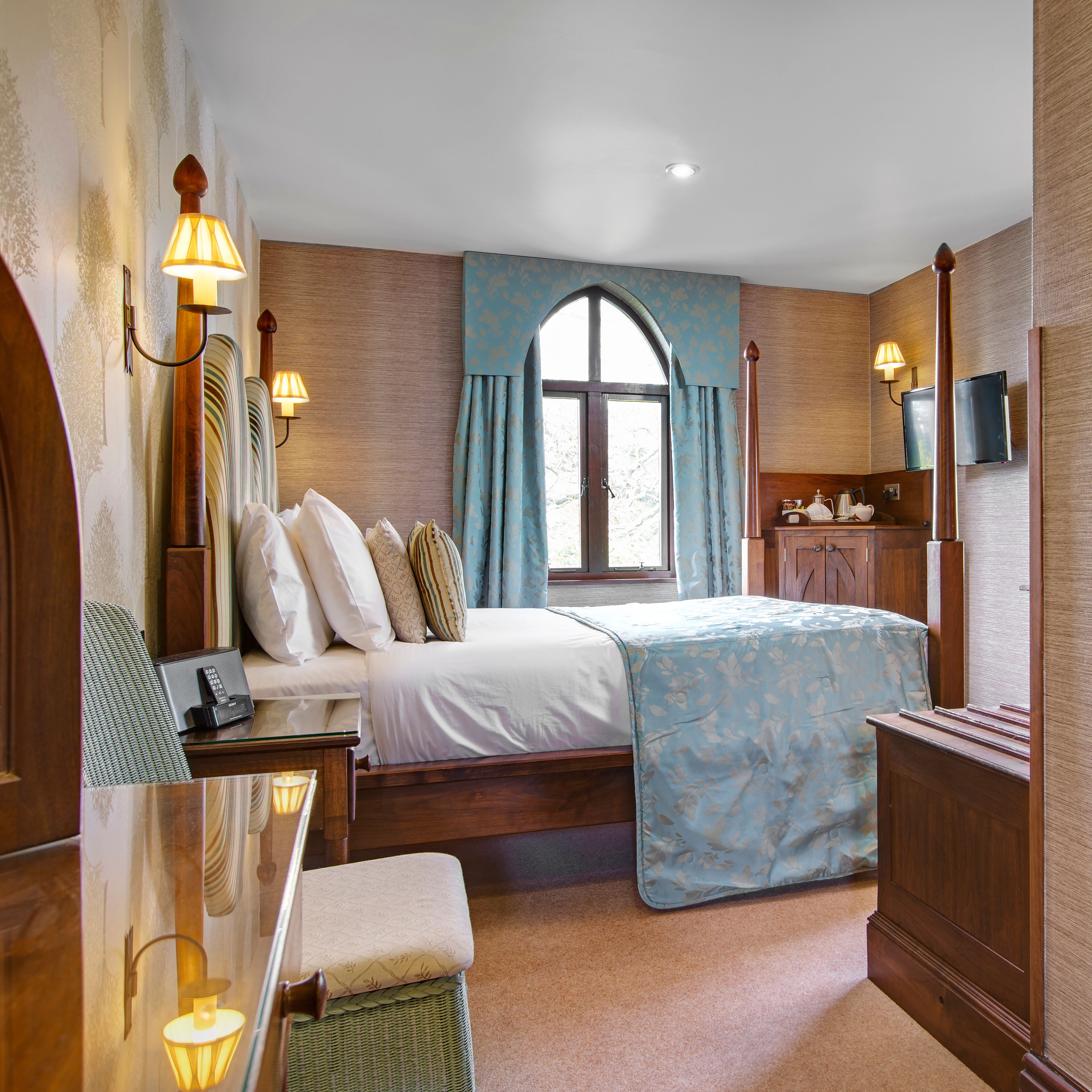Cozy hotel bedroom with four-poster bed, blue accents and a window