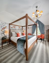 Elegant bedroom with a four-poster bed, decorative wallpaper, and vibrant accents