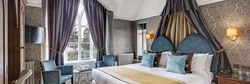 Elegant hotel bedroom with large bed, ornate curtains, and stylish seating area.