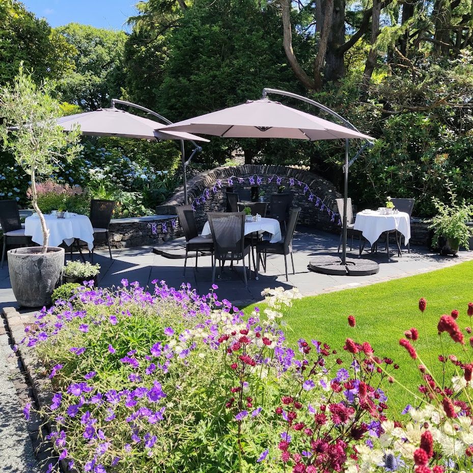 Outdoor patio with dining tables, umbrellas, and garden flowers