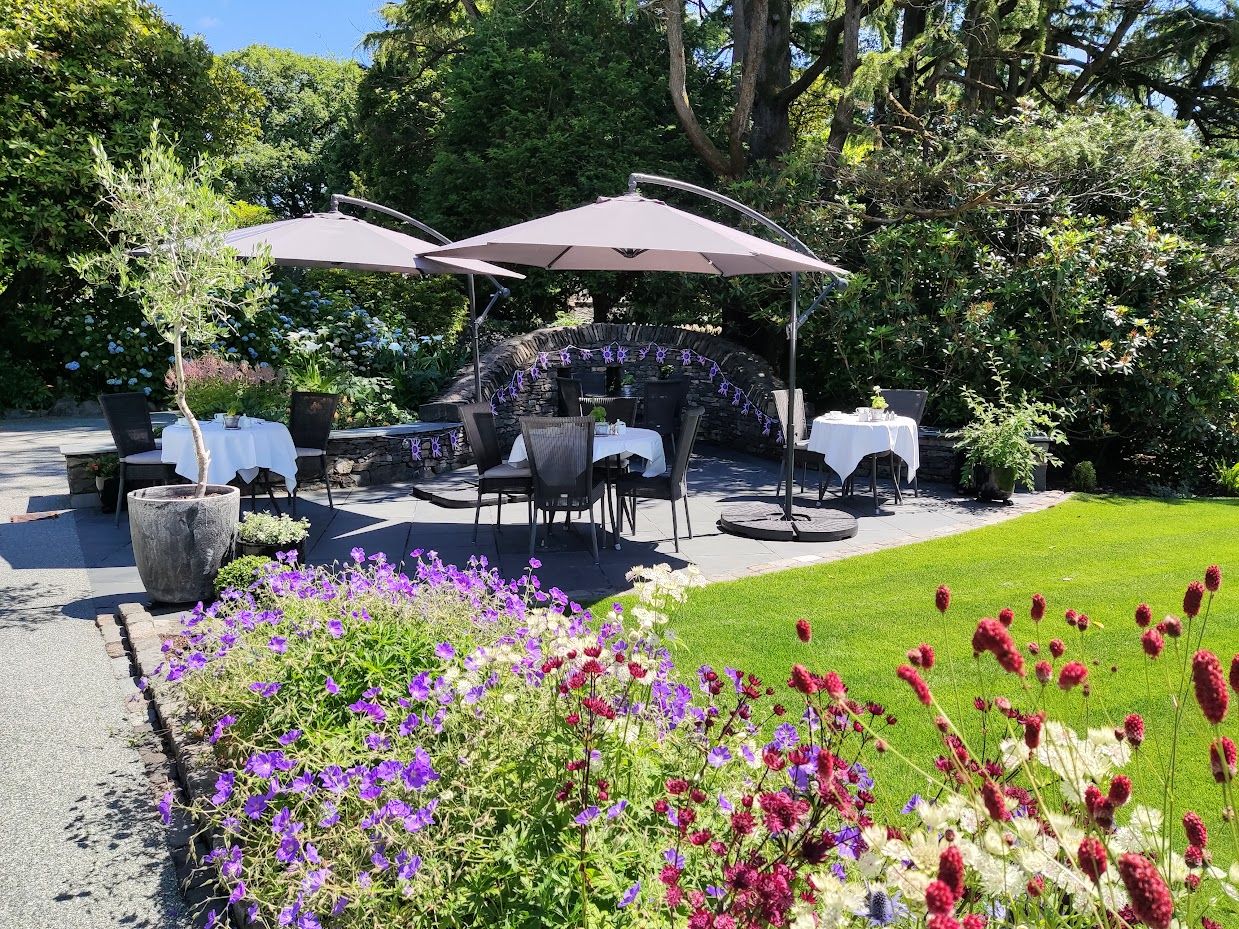 Outdoor patio with dining tables, umbrellas, and garden flowers