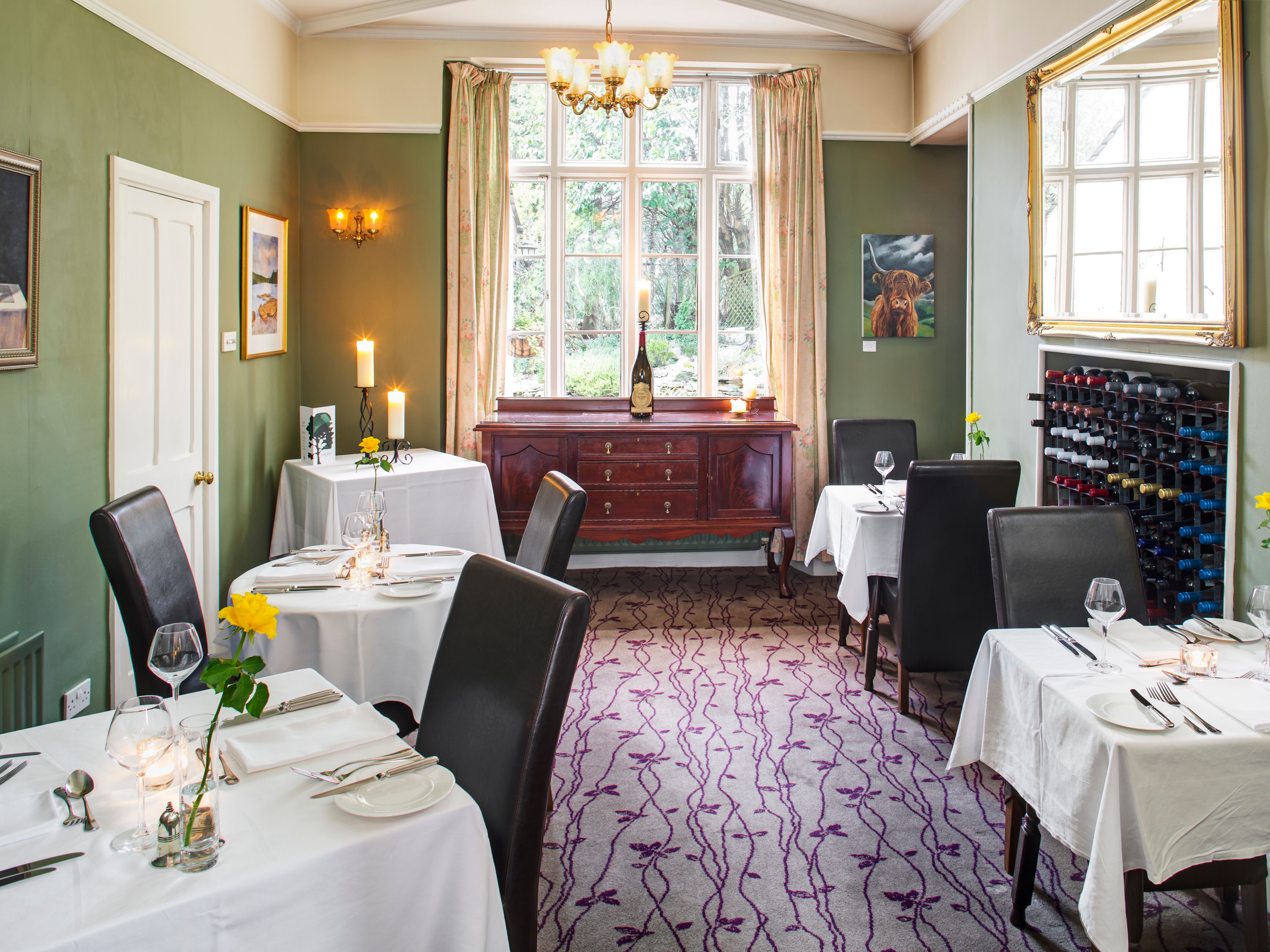 Elegant restaurant dining room with white tablecloths, wine rack, and large window.