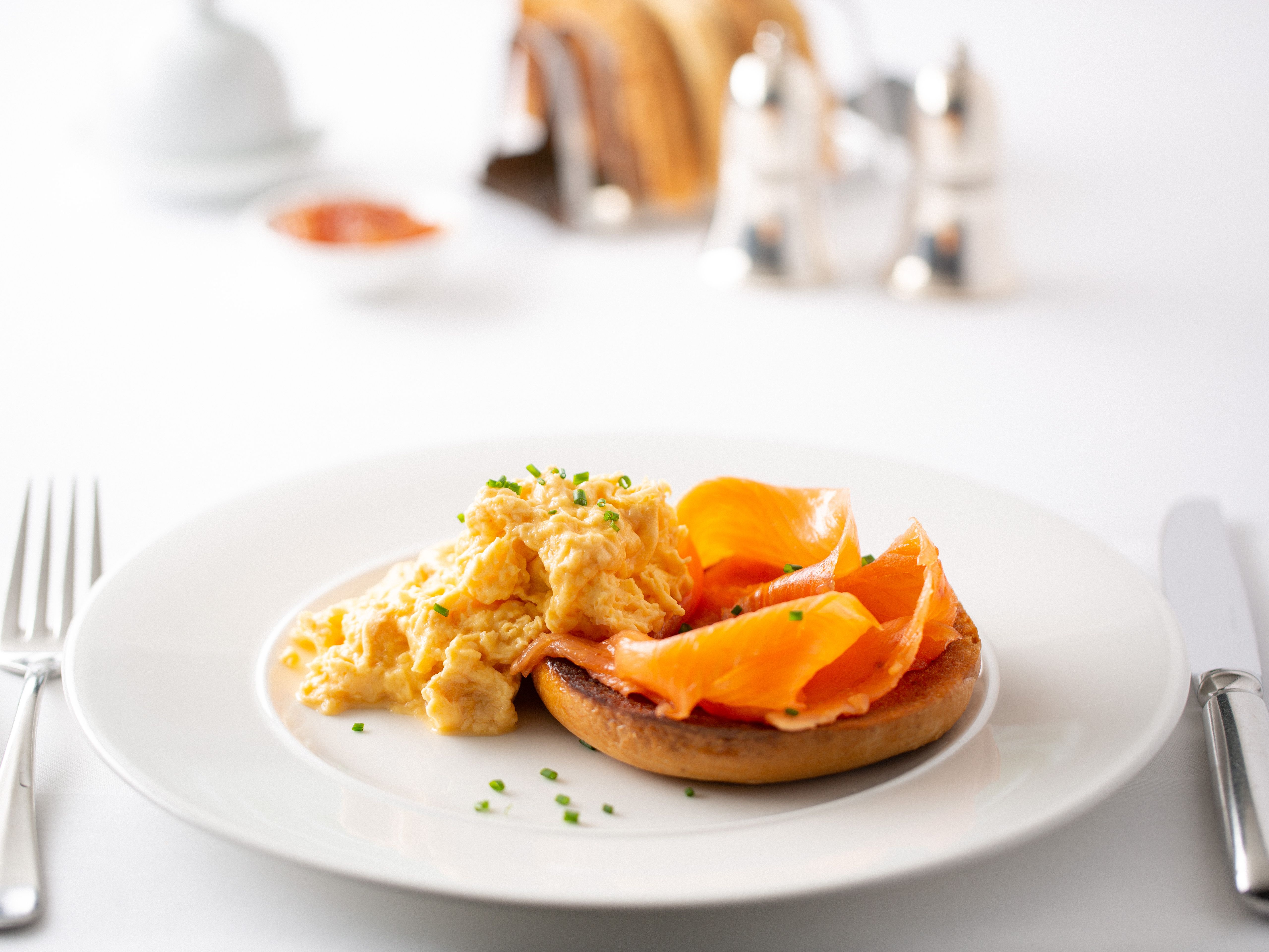 Scrambled eggs and smoked salmon on a toasted English muffin on a white plate