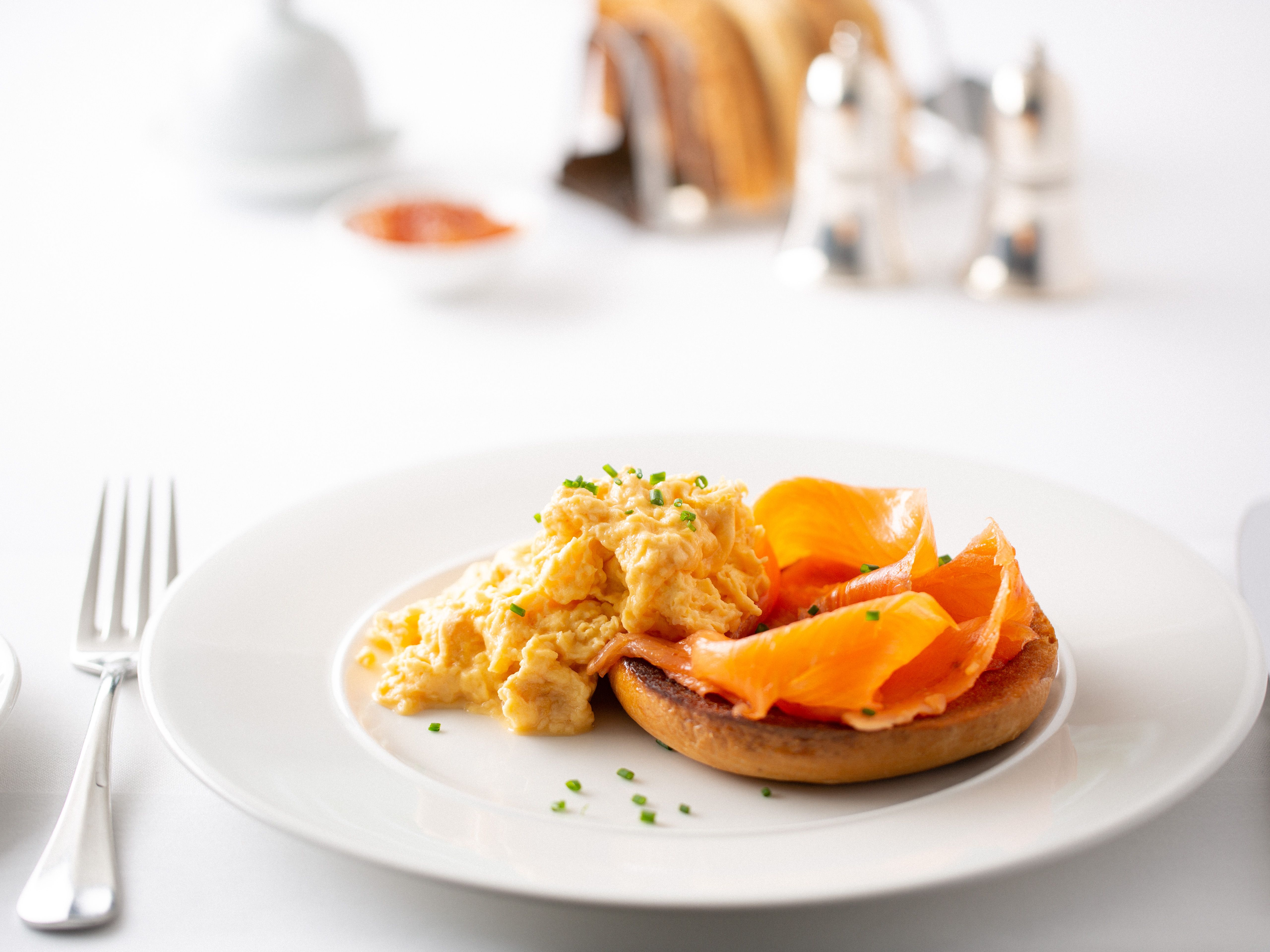 Scrambled eggs and smoked salmon on a toasted English muffin on a white plate
