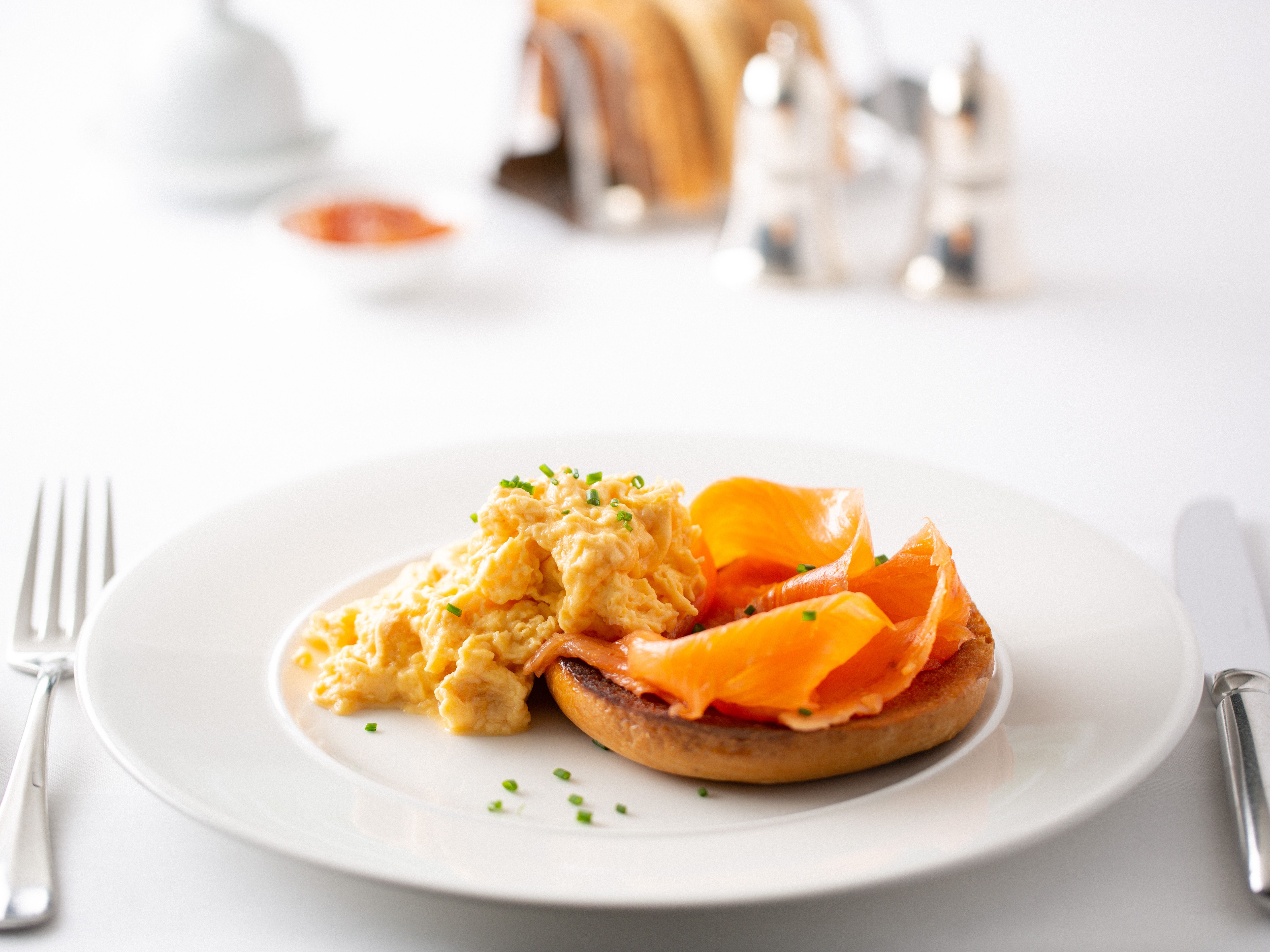 Scrambled eggs and smoked salmon on a toasted English muffin on a white plate