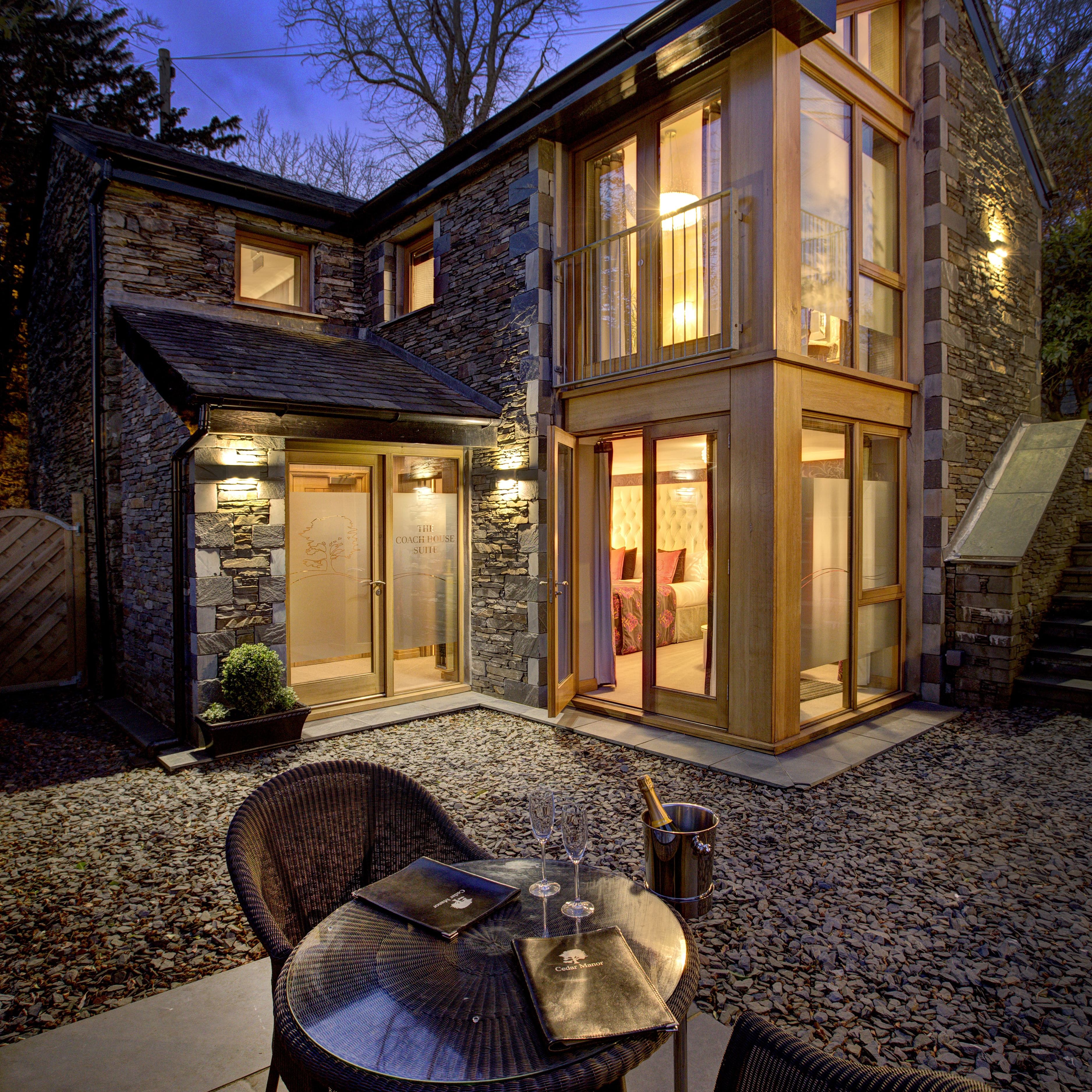 Modern stone house with large windows and patio seating at dusk