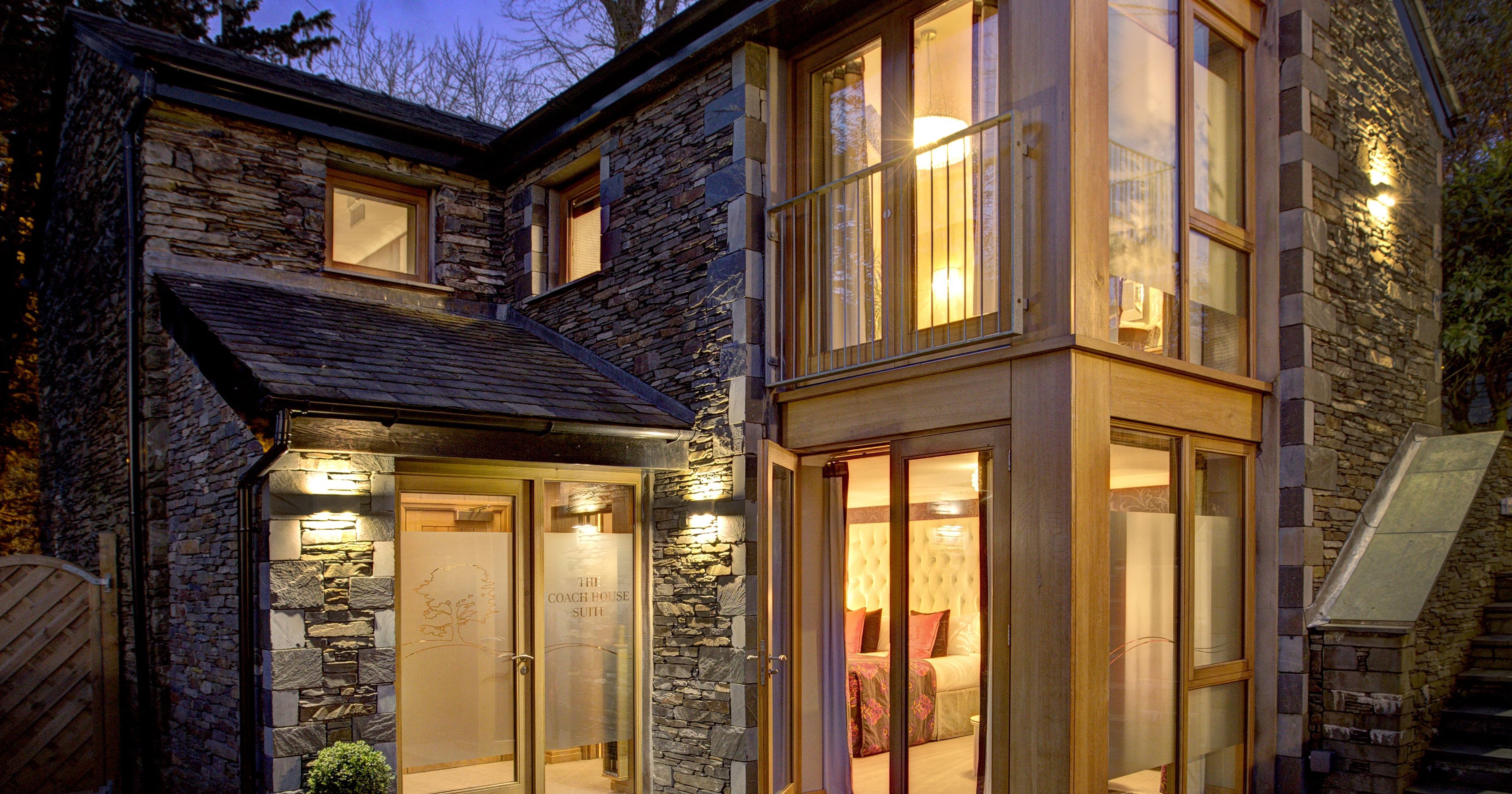 Modern stone house with large windows and patio seating at dusk