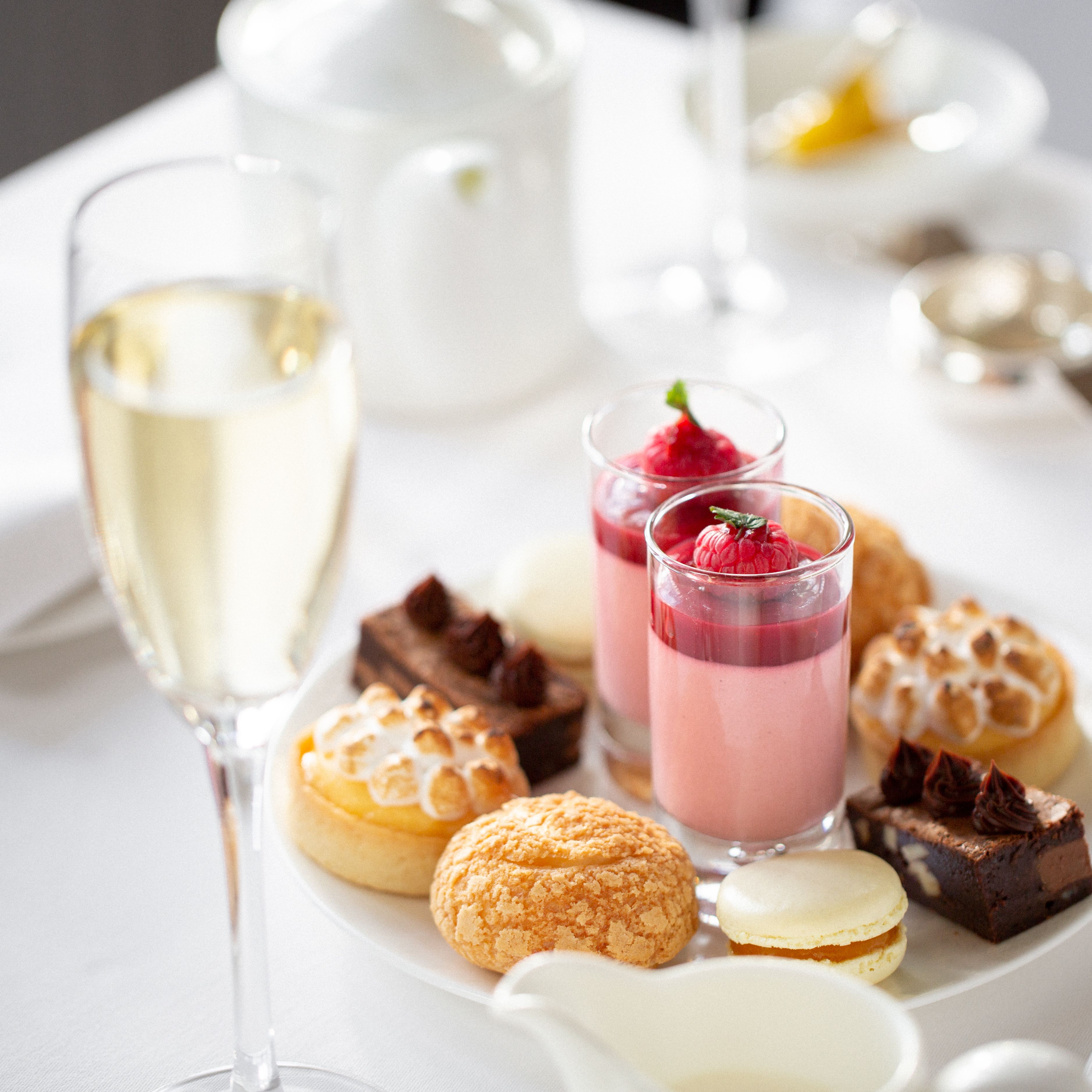 Assorted desserts and pastries on a white plate with a glass of sparkling wine